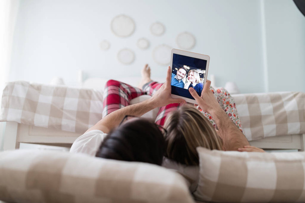 Joven pareja atractiva utilizando juntos tableta digital en el dormitorio
 - Foto, imagen