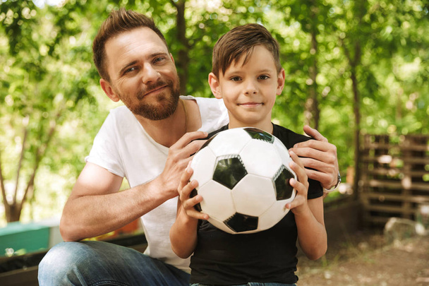 Picture of happy young father have fun with his little son outdoors in park nature with football ball. - Fotografie, Obrázek