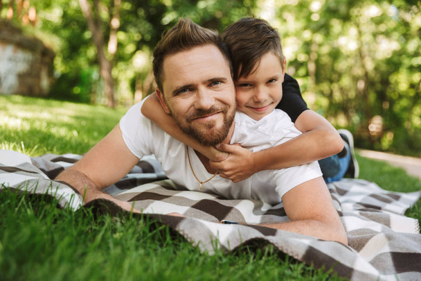Image of happy young father have fun with his little son outdoors in park nature. - Photo, image
