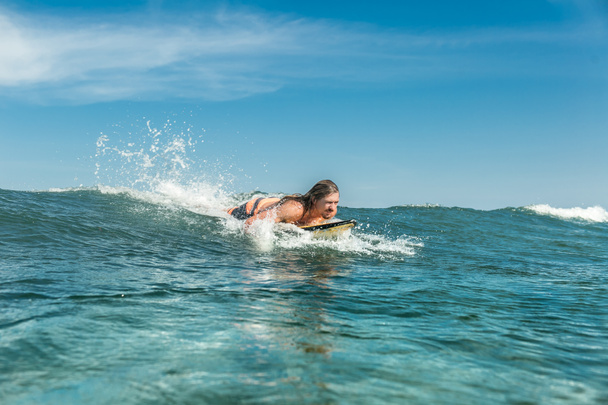 male athlete swimming on surfing board in ocean at Nusa Dua Beach, Bali, Indonesia - Photo, Image