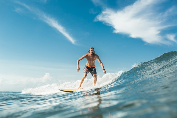 shirtless male surfer riding waves in ocean at Nusa Dua Beach, Bali, Indonesia - 写真・画像
