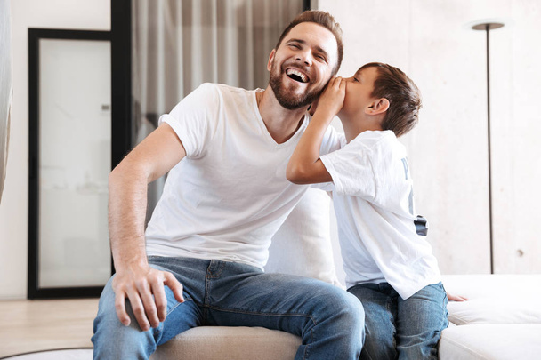 Image of happy young man father dad talking having fun with his son indoors at home. - Φωτογραφία, εικόνα