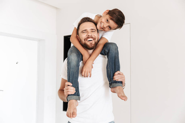 Photo of happy young man father dad having fun with his son indoors at home. - Φωτογραφία, εικόνα