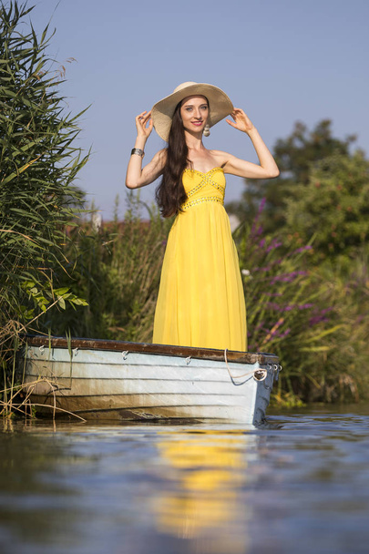 Attractive young woman with long brunette hair on a boat - Фото, изображение