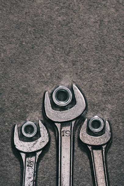 top view of wrenches and nuts on grey surface - Fotografie, Obrázek