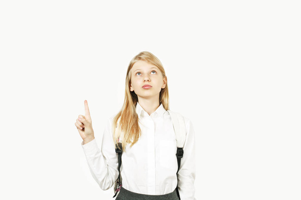 Close up portrait of young beautiful happy teenage school girl smiling wide, perfect teeth, standing on white background looking pointing up with index finger. Back to school sale concept. Copy space. - Foto, Bild