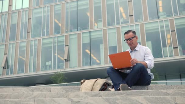 Człowiek siedzący na schodach i pracę na laptopie - Materiał filmowy, wideo