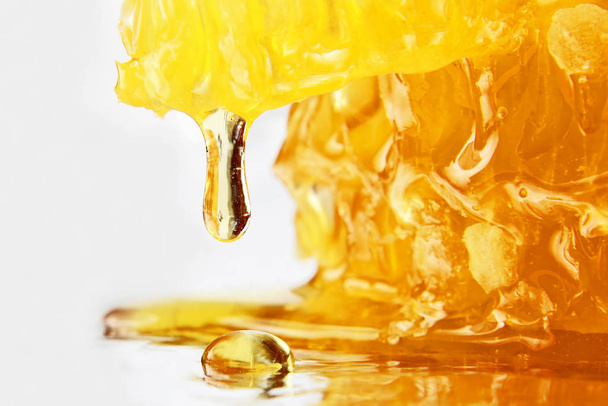 drop of honey dripping from the honeycomb closeup - Foto, immagini