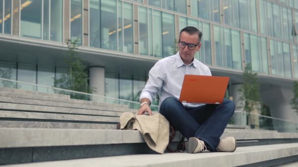 Człowiek siedzący na schodach i pracę na laptopie - Materiał filmowy, wideo