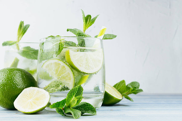 Mojito in two glasses with mint, slices lime, ice cubes, straw on soft white background, copy space. - Φωτογραφία, εικόνα