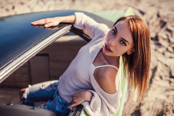 Feel the spirit of adventure! Attractive young woman is leaning out of the window of green retro car. Vintage classic car. - Foto, Bild