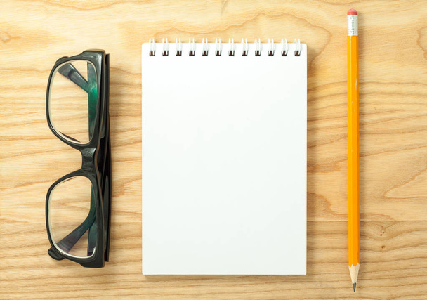 Vista superior del cuaderno en blanco espiral abierto, vasos y lápiz sobre fondo de escritorio de madera
 - Foto, Imagen
