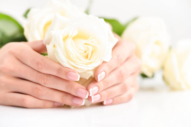 Hands of a woman with beautiful french manicure and white roses - Fotó, kép