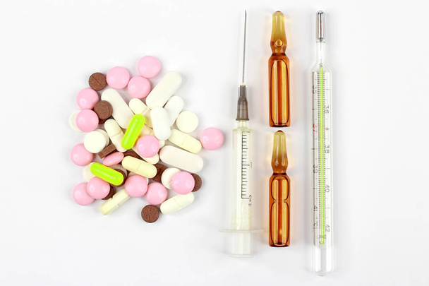 léčivé tablety, ampule pro injekce, teploměr, stříkačku na bílém pozadí - Fotografie, Obrázek