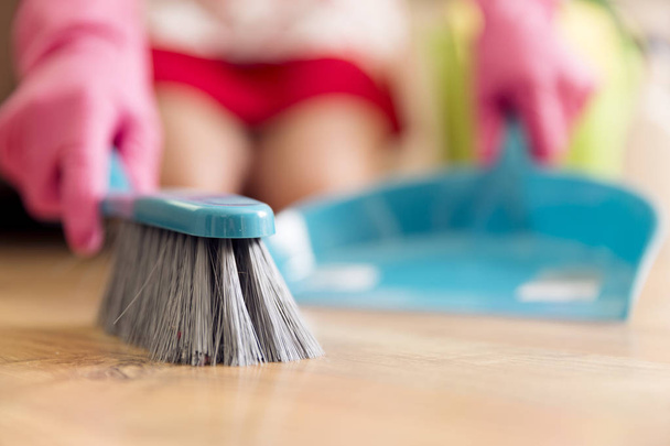 Concepto de trabajo doméstico, limpieza y limpieza: mujer con cepillo y suelo de barredora en casa
 - Foto, Imagen