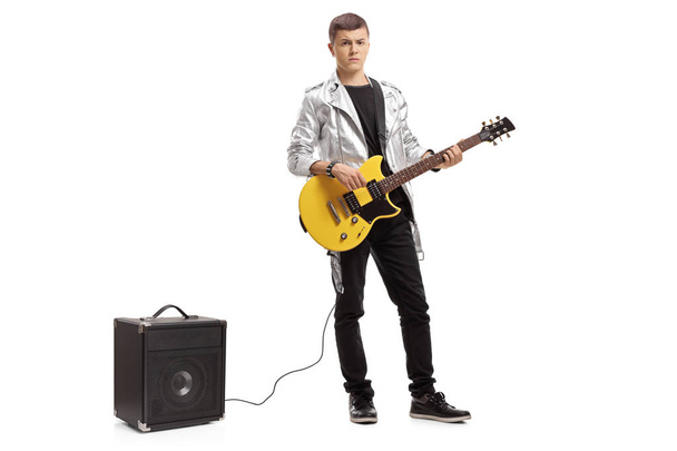 Full length portrait of a teenager with an electric guitar and an amplifier isolated on white background - Foto, imagen