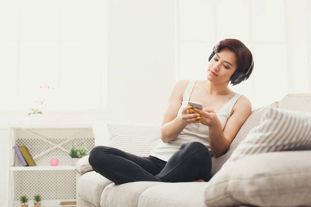 Young woman in headphones on beige couch - Foto, Imagem