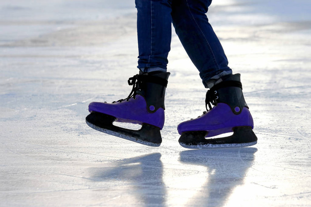 feet on the skates of a person rolling on the ice rin - Foto, afbeelding