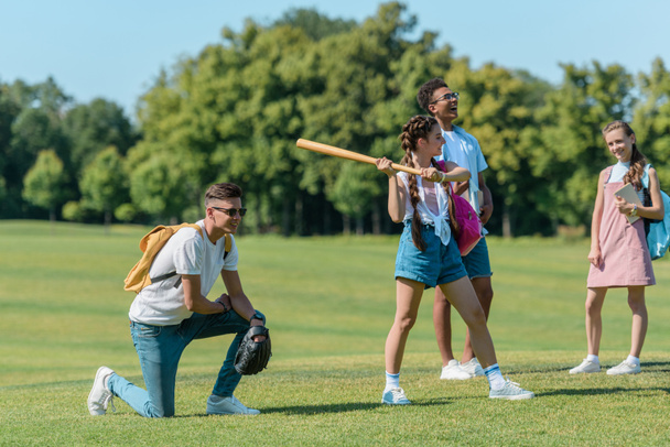 multiethnic group of teenagers playing baseball together in park - Foto, Bild