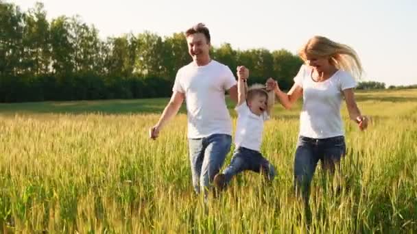 Boldog család: apa, anya és fia, futás-ban mező öltözött fehér pólók - Felvétel, videó