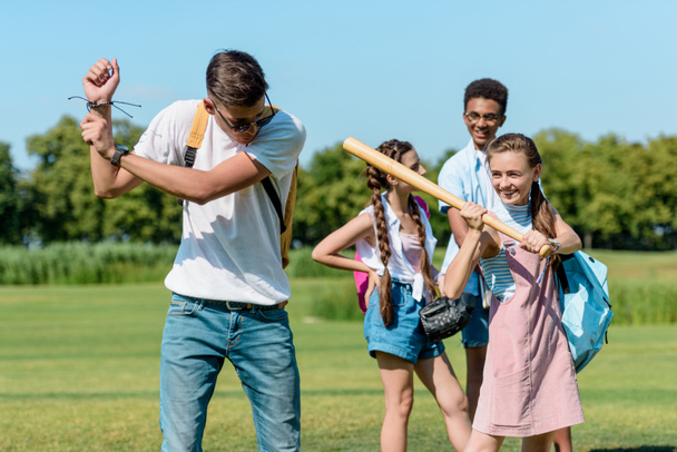 smiling teenagers having fun and playing baseball in park - Фото, зображення