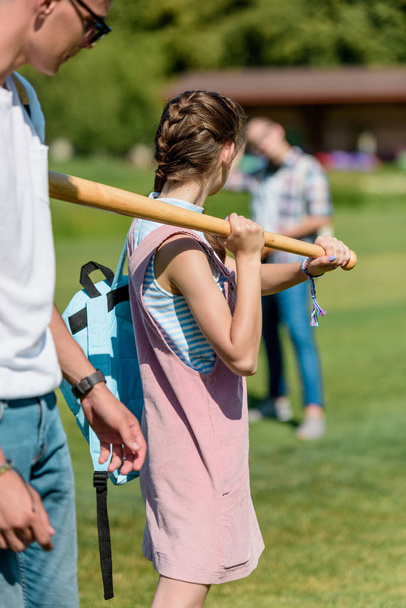 teenage girl holding baseball bat and playing with friends in park - Photo, Image