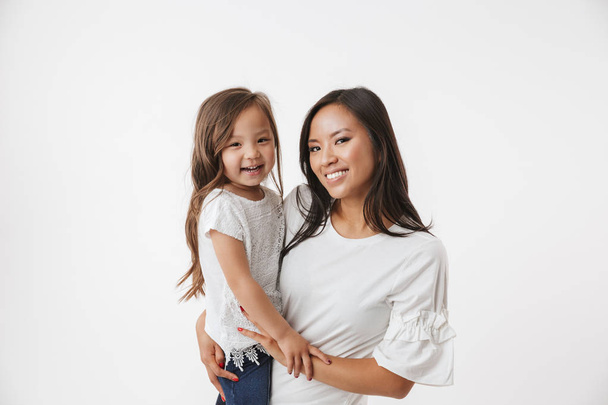Photo of cheerful young asian woman mother with her little girl child daughter isolated over white wall background. - 写真・画像