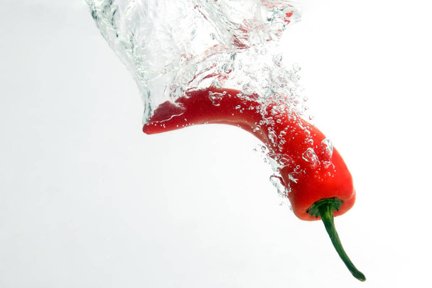 Κόκκινο καυτερό πιπέρι που πέφτει στο νερό - Φωτογραφία, εικόνα