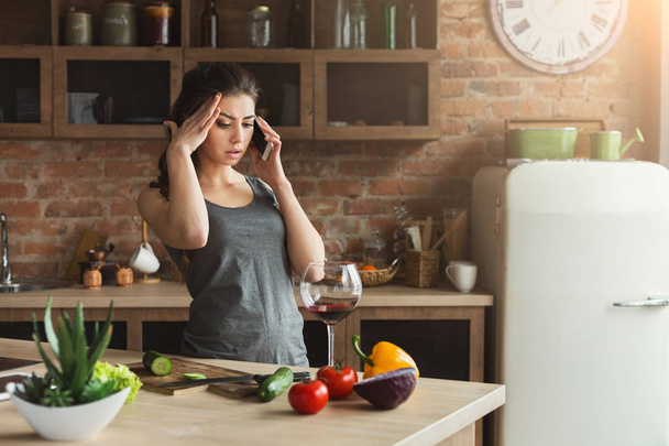 Donna preoccupata che parla al telefono in cucina di casa
 - Foto, immagini