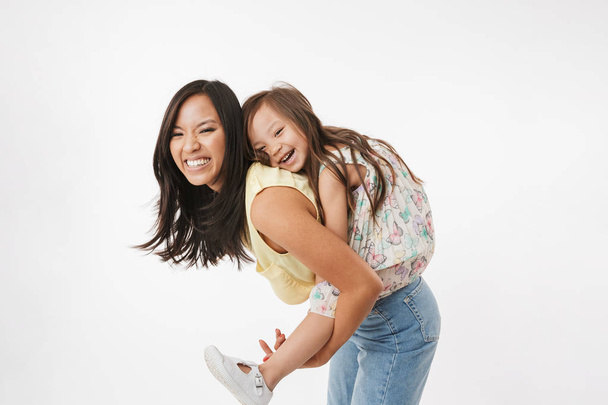 Image of happy young asian woman mother having fun with her little girl child daughter isolated over white wall background. - Φωτογραφία, εικόνα