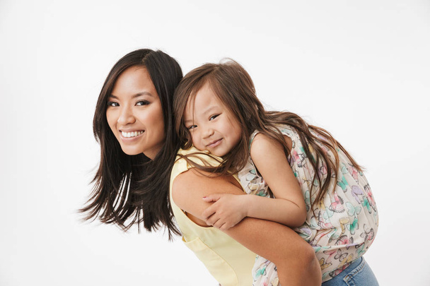 Image of happy young asian woman mother having fun with her little girl child daughter isolated over white wall background. - Φωτογραφία, εικόνα