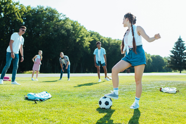 公園でサッカー ボールで遊んで幸せな十代の多民族の友人   - 写真・画像