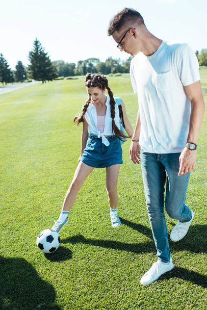 happy teenage boy and girl playing with soccer ball in park - Fotó, kép