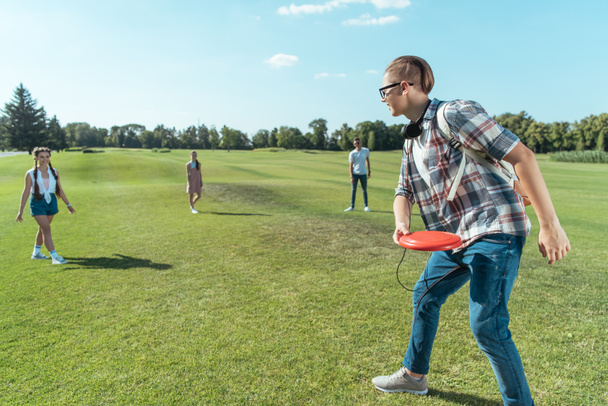 group of happy teenage friends playing with flying disc in park - Fotoğraf, Görsel