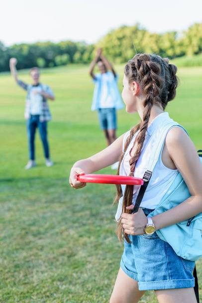 beautiful teenage girl throwing flying disc to friends in park - 写真・画像