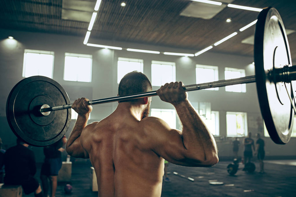 Fit young man lifting barbells working out in a gym - Photo, Image