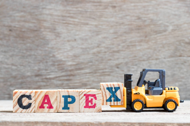 Zabawka wózek widłowy przytrzymaj literę bloku x, aby ukończyć wyraz capex (skrót od wydatków kapitałowych) na tle drewna - Zdjęcie, obraz