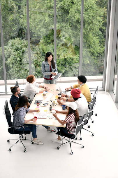 Dinleme ve ofiste bir meslektaşım tarafından bir sunum konusunda konuşurken bir masa etrafında oturup iş kişilerdir - Fotoğraf, Görsel