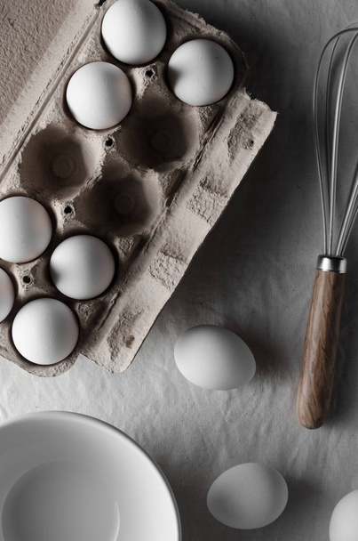 White eggs in an egg carton. White linen tablecloth background. - Фото, зображення