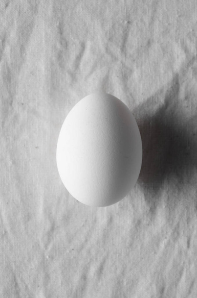 Close-up of white egg on a white linen tablecloth background. - 写真・画像