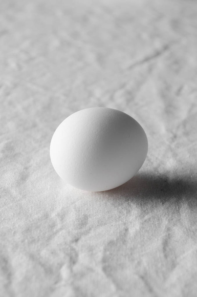 Close-up of white egg on a white linen tablecloth background. - Foto, Bild