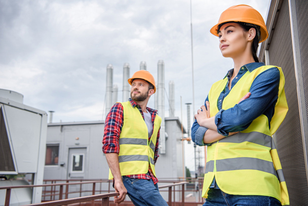 professional engineers in safety vests and helmets posing on roof - Photo, Image