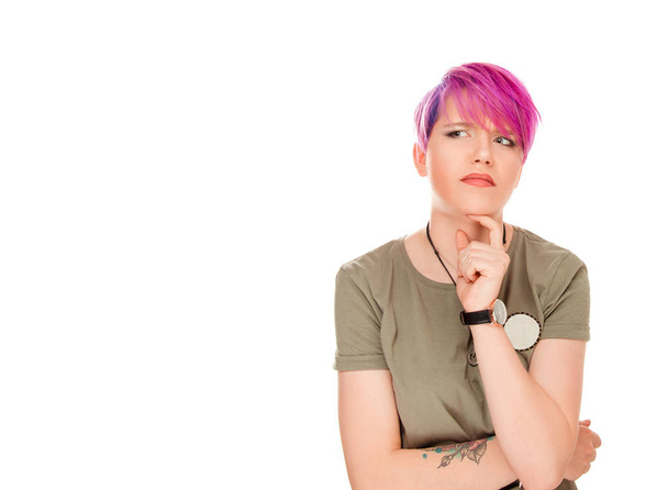 Jovem mulher pensativa com cabelo rosa curto tocando queixo em dúvidas enquanto olha para longe e pensando na decisão isolada no fundo branco
 - Foto, Imagem
