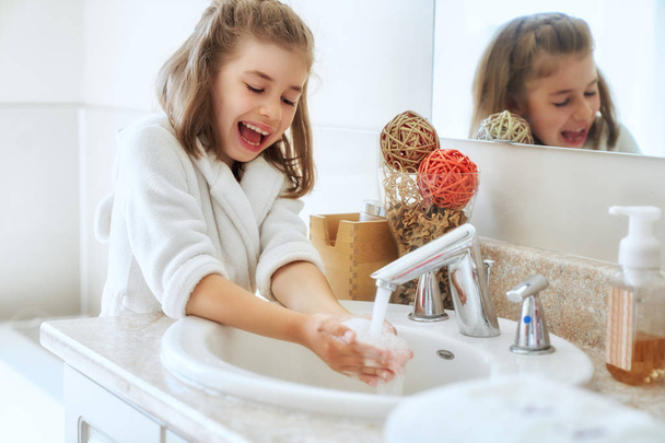 Cute little girl is washing hands under running water. - Photo, image