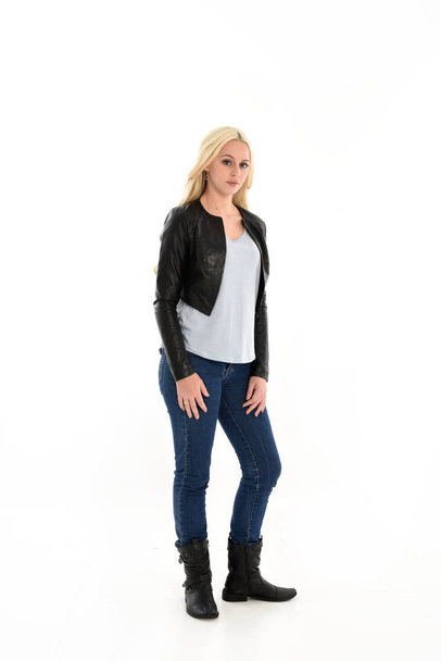 full length portrait o blonde girl wearing leather jacket and jeans. standing pose, isolated against white studio background. - Fotoğraf, Görsel