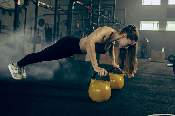 Fit young woman lifting barbells working out in a gym - Foto, Imagem