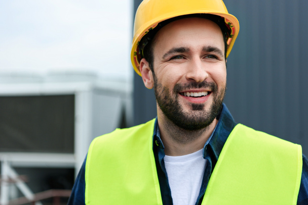 portrait of cheerful male engineer in safety vest and helmet - Photo, Image