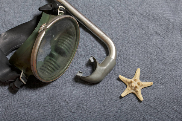 Going on vacation on the beach. Mask for swimming under water and a tube on a gray background. Nearby is the starfish. - Фото, изображение