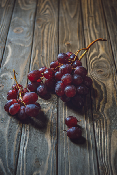 close-up shot of branches of red grapes on rustic wooden table - Photo, Image