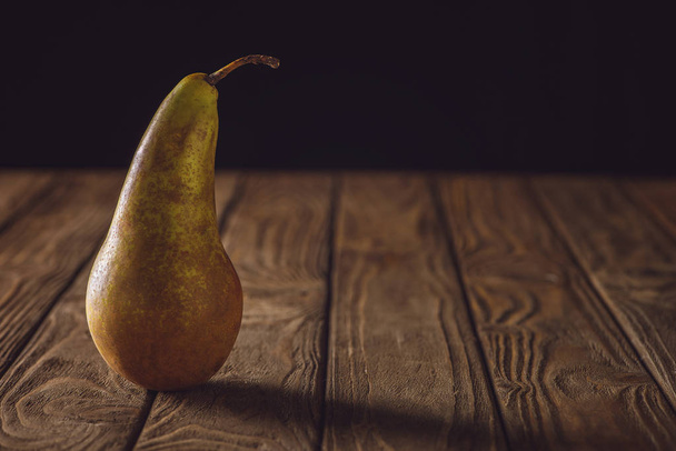 close-up shot of ripe pear on rustic wooden table on black - Fotó, kép